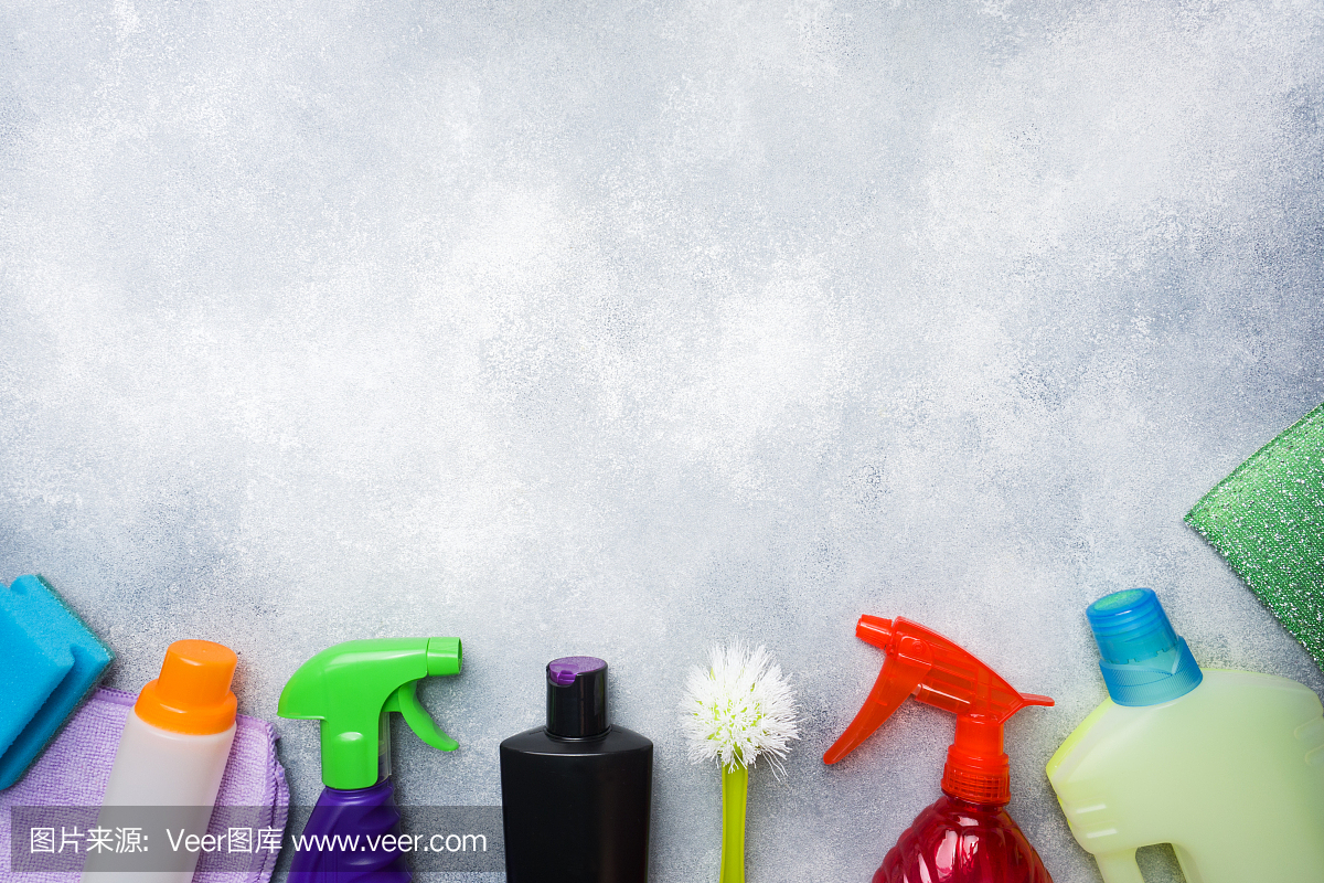 瓶子與洗滌劑,刷子和海綿在混凝土背景。色彩鮮艷的清潔產(chǎn)品。家庭清潔的概念。俯視圖,復制空間。